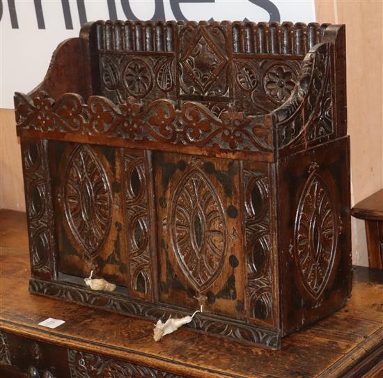 A heavily carved oak cabinet with two sliding doors W.60cm